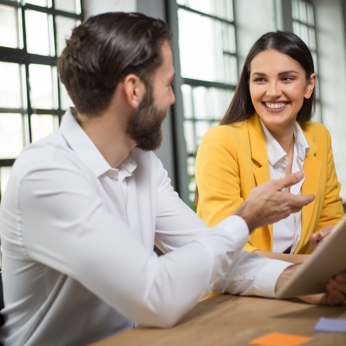 Two people talking by a laptop
